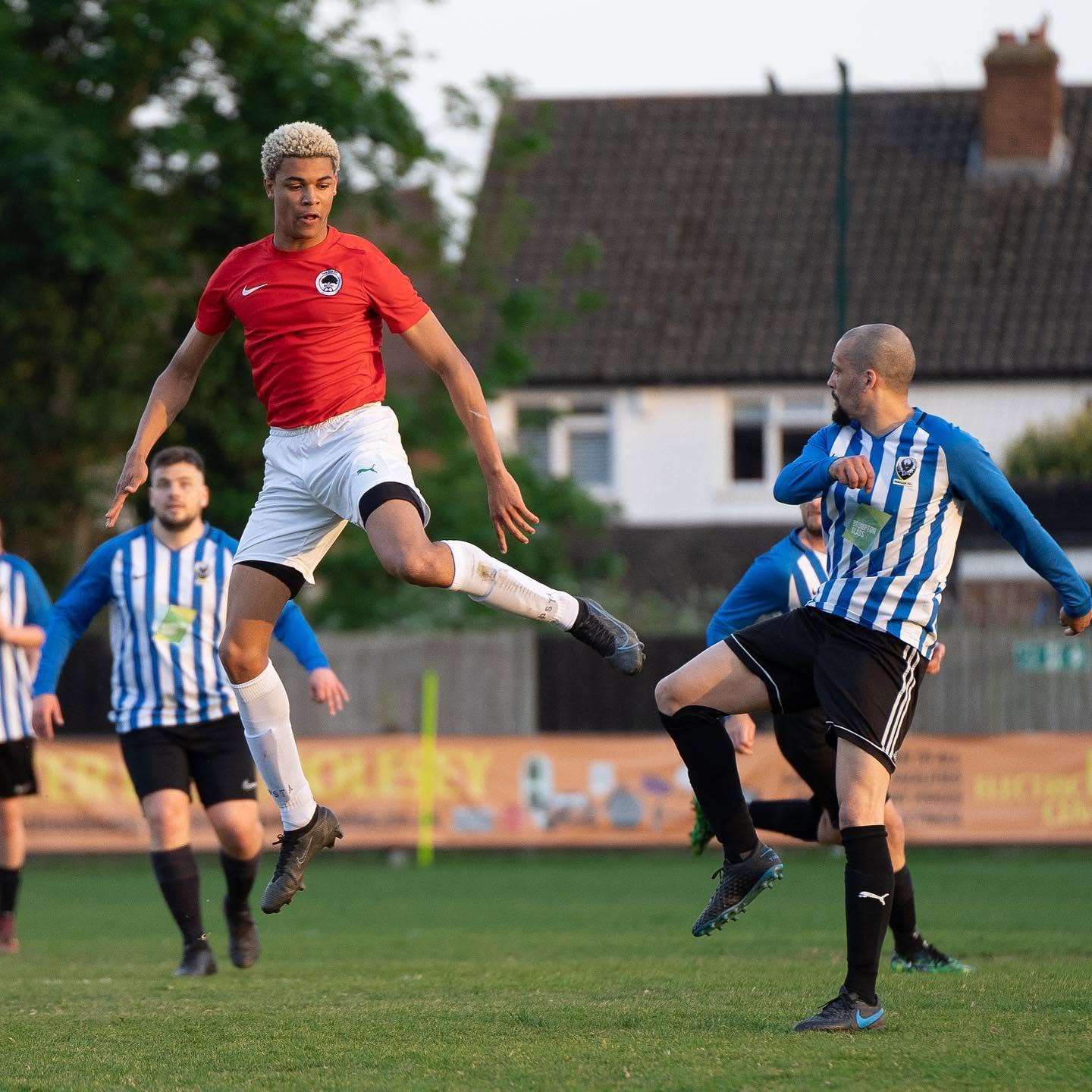 New Elm player in red jumping for the ball
